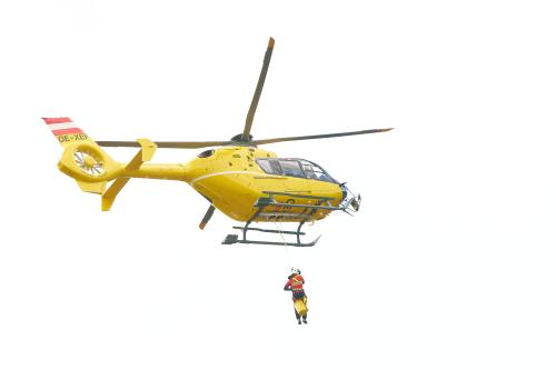 Ein Bergretter hängt unter dem Hubschrauber und ist bereit für eine Rettung.